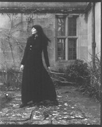 a black and white photo of a woman in a long black coat