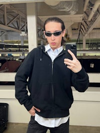 a man wearing sunglasses and a black hoodie taking a selfie