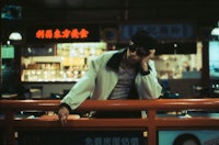 a man leaning against a railing in an asian restaurant