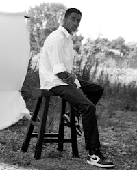 a man sitting on a stool in front of a camera