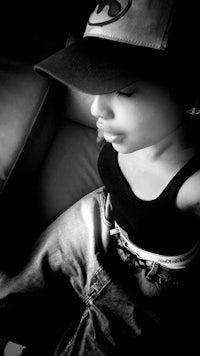 a black and white photo of a girl wearing a baseball cap