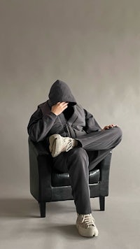 a man in a hoodie sitting in a chair