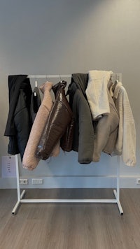 a rack with several coats hanging in front of a wall