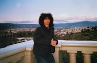 a man standing on a balcony with a view of a city