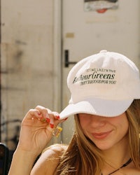 a young woman wearing a white baseball cap