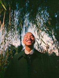 a man wearing a suit and tie in front of a tree