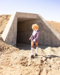 a woman is standing in a tunnel in the desert