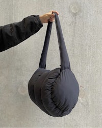 a person is holding a black bag up against a wall