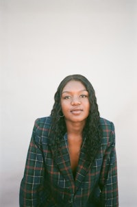 a black woman in a plaid jacket posing for a photo