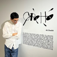 a man leaning against a wall with writing on it