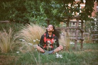 a young woman sitting in the grass and meditating