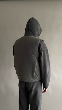 the back of a man wearing a grey hooded vest