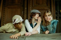 three young women sitting on a wooden table