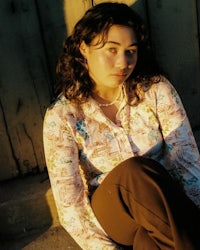 a woman in a floral shirt sitting on the ground