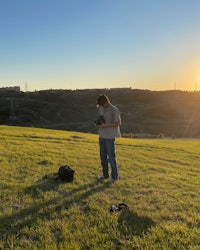 a man standing in a grassy field at sunset