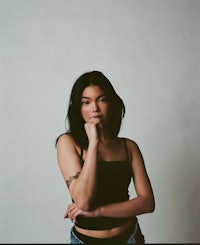 a woman in a black top posing with her hand on her chin