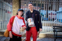 a man and woman standing next to each other holding a bucket